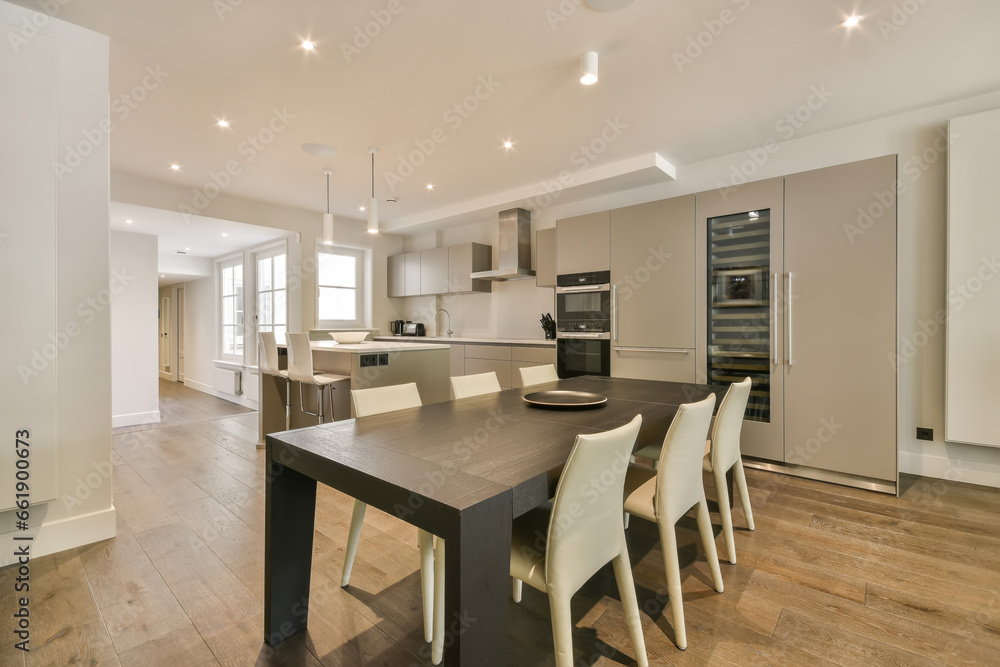 a kitchen and dining area in a modern apartment with wood flooring, white walls and light fixtures on the ceiling