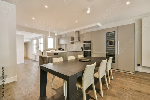 a kitchen and dining area in a modern apartment with wood flooring  white walls and light fixtures on the ceiling