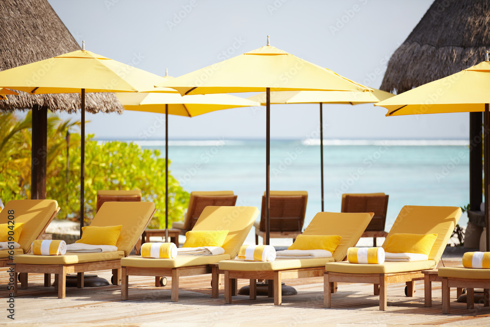 Maldives, deck chairs and umbrella on beach for luxury, travel or summer villa for vacation or holiday. Tropical, leisure and ocean for resort, relax and island with sunshine, outdoor or caribbean