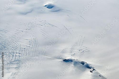 Fényképezés Aerial view of mountains, snow fields, crevasses and glaciers of southern Greenland from airplane window on clear sunny autumn day