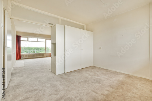 an empty room with white walls and carpeted floor  there is a large mirror on the wall to the right