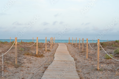 An idyllic landscape with a path with wooden tiles leading to the sea. Wooden seaside path on Platja de Canet, Canet d'en Berenguer, Sagunto, Spain. Scenic path to the sea.