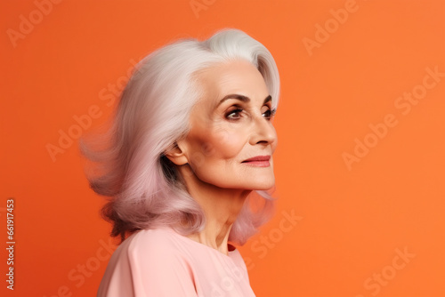 Beautiful modern elderly woman on orange background, portrait
