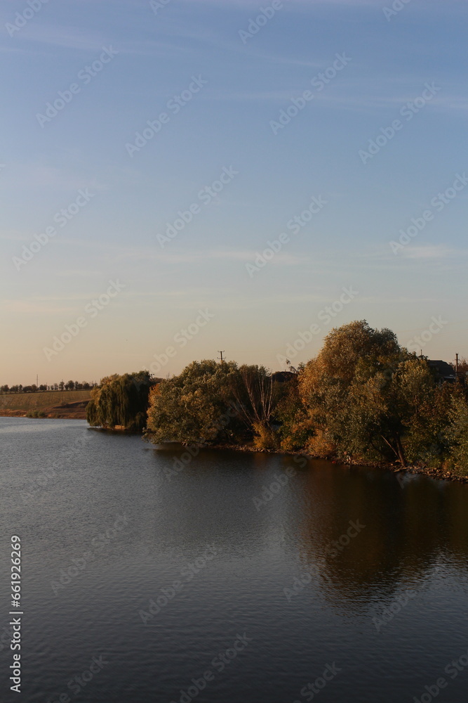 A body of water with trees and a blue sky