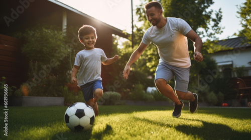 Joyful father and son play with a soccer ball in the front yard of the house © MP Studio