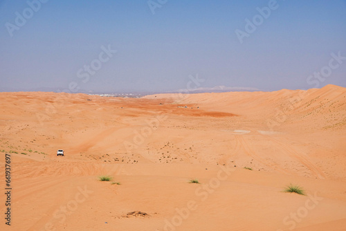 Wahiba sand orange desert on the horizon a white jeep. Oman.
