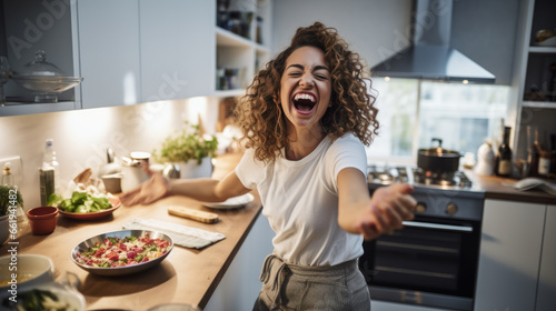 Young woman laughs while cooking in the kitchen