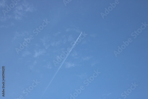 Aeroplane flying high in blue sky with jet contrails visible