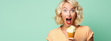 Surprised young woman with bright lips holding a delicious ice cream on flat pastel green background with copy space. 