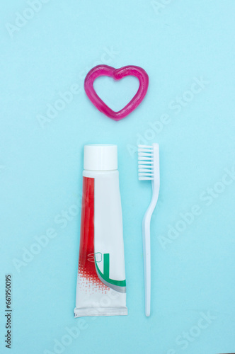 Closeup of a toothpaste, toothbrush and toothpaste heart on blurred blue background. Means to care for the oral cavity.