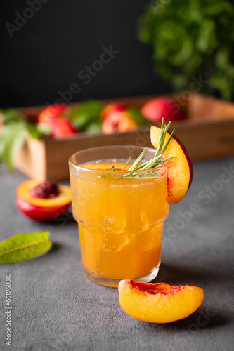 Peach tea with ice and rosemary on a glass. Vegan homemade healthy  drink on a dark background with fresh fruits.