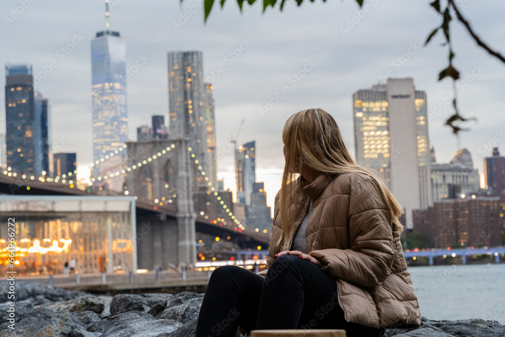 travel woman sitting in the beach looking new york city building in sunset travel woman sitting in the beach looking new york city building in sunset