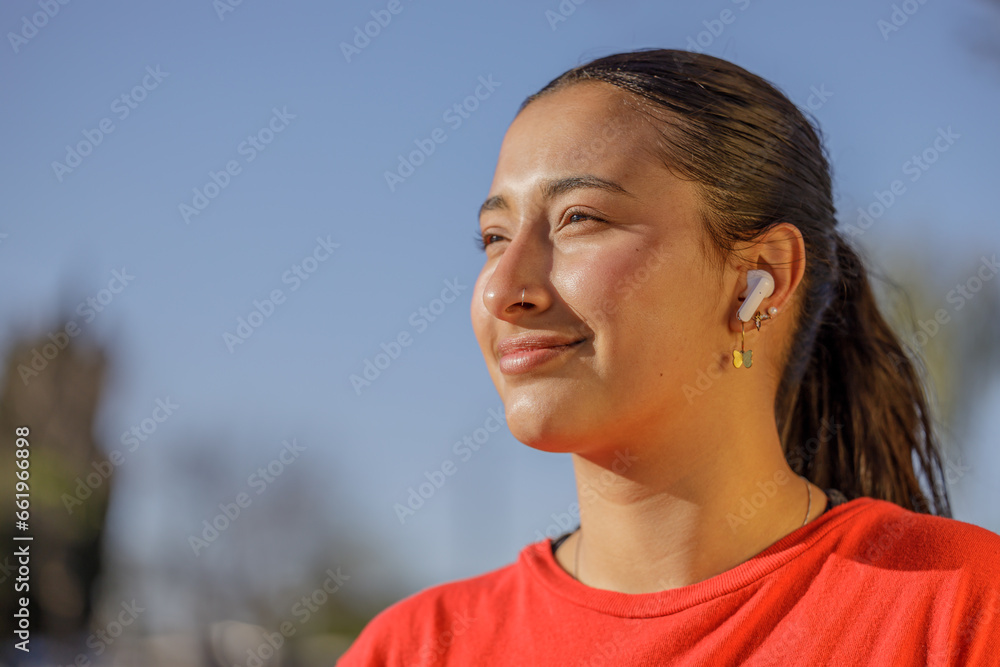Close-up portrait of a latin girl in sports style with headphones and a red t-shirt. Close-up portrait of a latin girl in sports style with headphones and a red t-shirt.