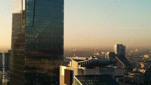 Modern business districtcity glass skyscrapers drone zoom in close to the buildings. Skyscraper in the big city top view during the sunrise when first sun rays are going through the glass windows. photo