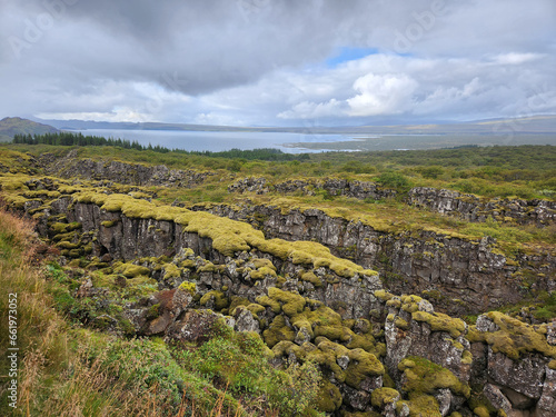 Moss covered lava ridges with Lake Myvatn in background in northern Iceland on sunny overcast autumn afternoon.