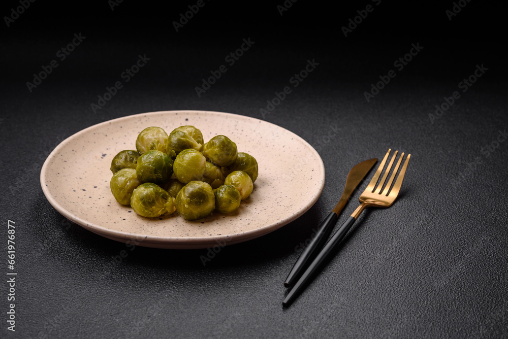 Delicious boiled Brussels sprouts on a ceramic plate on a dark concrete background Delicious boiled Brussels sprouts on a ceramic plate on a dark concrete background
