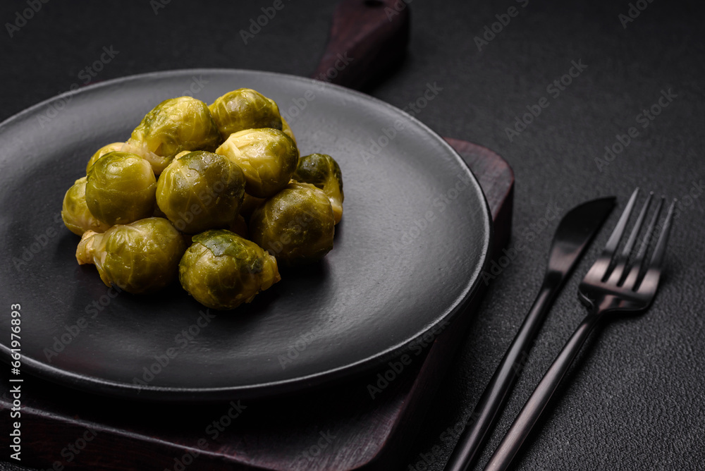 Delicious boiled Brussels sprouts on a ceramic plate on a dark concrete background Delicious boiled Brussels sprouts on a ceramic plate on a dark concrete background