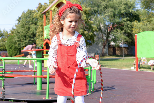 Little girl is playing on the children's playground with hulahop photo