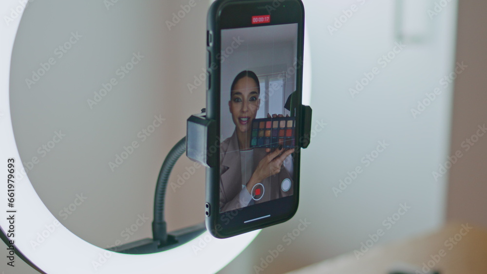 Fototapeta premium Smartphone view blogger broadcasting cosmetics review closeup. Woman streaming