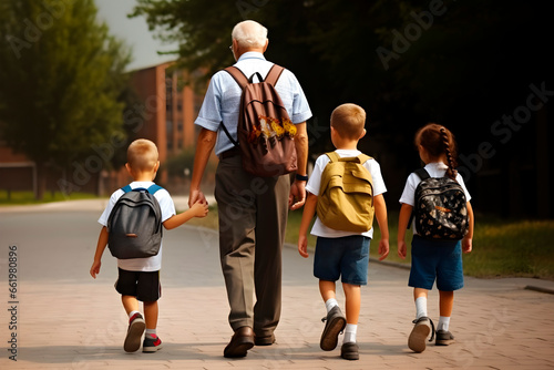 grandfather taking his grandchildren on their uniforms with their backpacks to school, taking one of them by the hand, in line side by side, horizontal