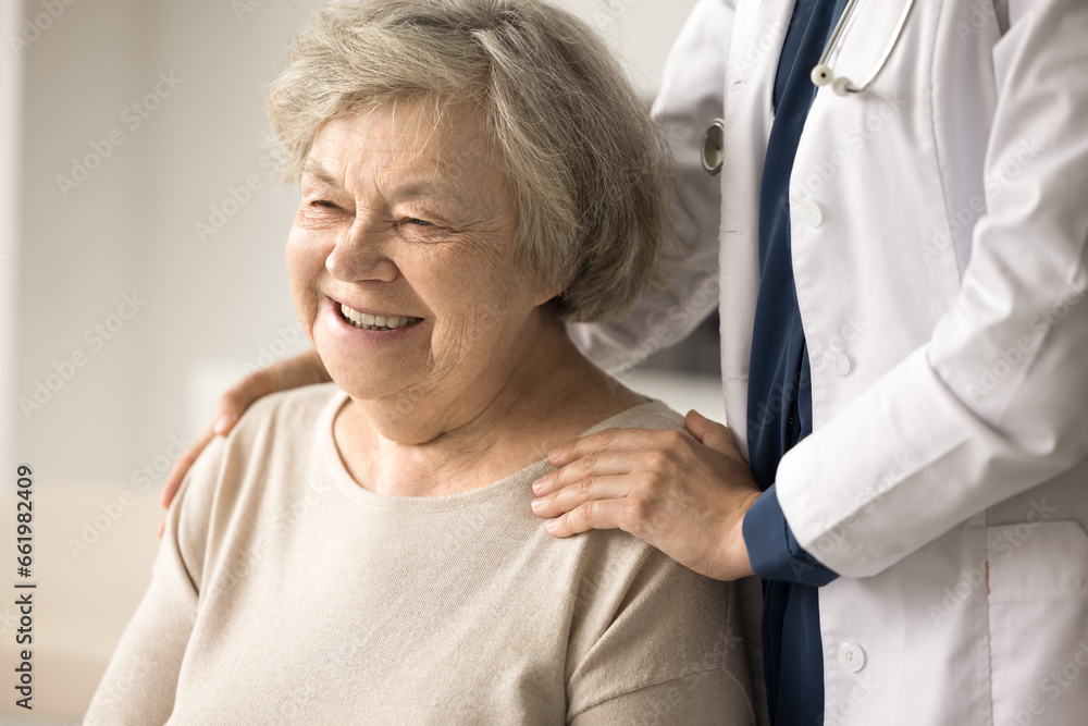 Close up portrait of happy female pensioner enjoy professional medical care in clinic. Woman physician support older patient touch shoulders, give psychological aid. Geriatrics, healthcare, services Close up portrait of happy female pensioner enjoy professional medical care in clinic. Woman physician support older patient touch shoulders, give psychological aid. Geriatrics, healthcare, services