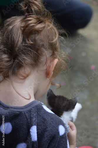 a little girl is holding a little kitten