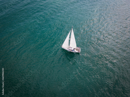 Aerial view of a sailboat gracefully gliding across the boundless waves of the sea. © sandsun