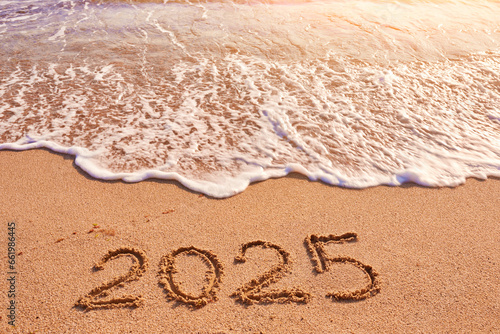 2025 year written on sandy beach sea at sunny day