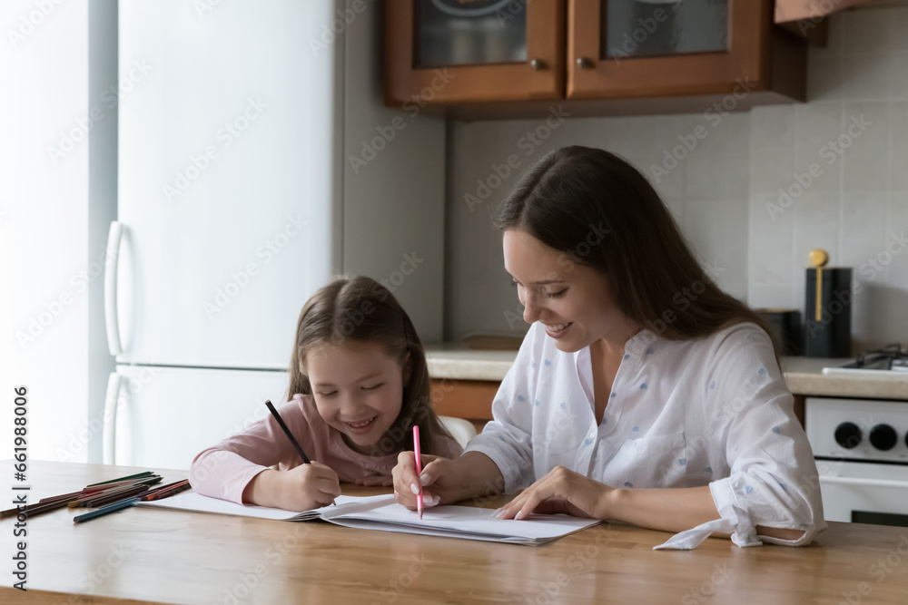 Happy mom and sweet little child girl drawing colorful doodles in paper album, together. Mother and kid enjoying home leisure, training artistic skills at kitchen table. Family, motherhood concept Happy mom and sweet little child girl drawing colorful doodles in paper album, together. Mother and kid enjoying home leisure, training artistic skills at kitchen table. Family, motherhood concept