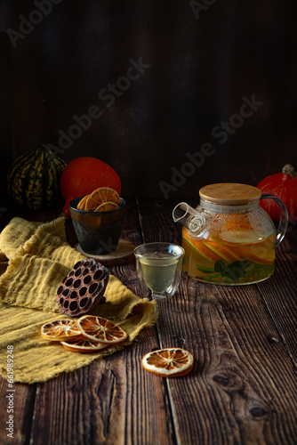 Fruit tea with oranges and mint in glass kettle on wooden table 