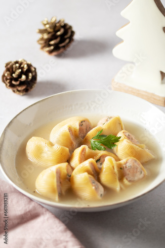 Traditional Catalan Christmas dish Escudella in white plate on table, stuffed pasta in meat broth, top view