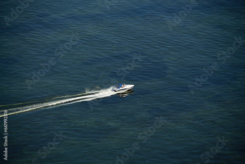 motor boat in the sea. Top view of the boat. Top view of a white boat sailing in the blue sea. A boat with a motor on blue water. © Yashina