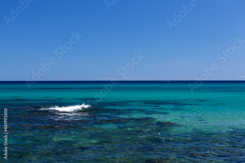 Beautiful clear and still blue turqoise water of Mediterranean sea with blue sky at Sardinia, Italy on sunny day.