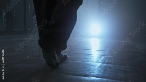 Young woman entering stage with smoke on background. Close-up of woman legs entering stage. Elegant female heels dancer. Silhouette of dancer legs walking through dark studio. Tracking shot in 4K, UHD