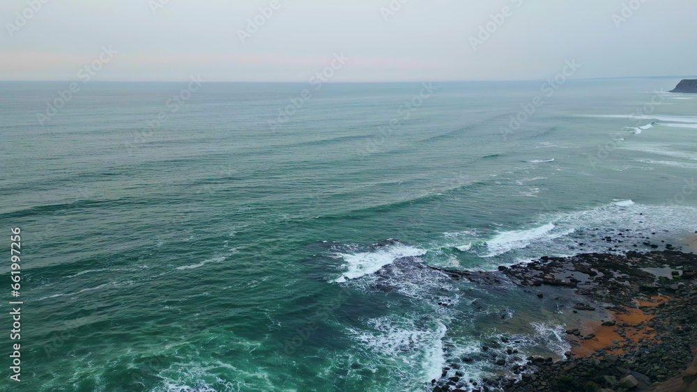 Dramatic cloudy marine panorama aerial view. Foamy ocean waves covering beach