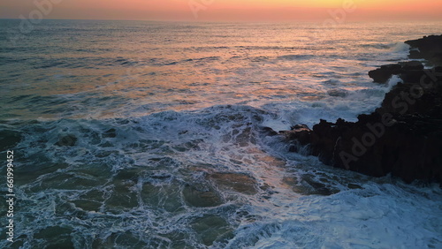 Fotografie Dramatic sea foaming shoreline stones sunset