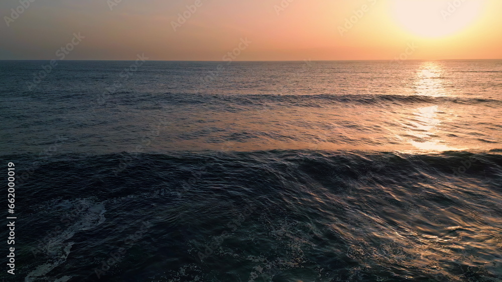 Waving marine water sunset aerial view. Golden dawn sky over stormy sea surface