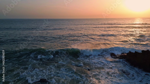 Stunning aerial foaming ocean crashing cliff. Sea waves breaking rock silhouette