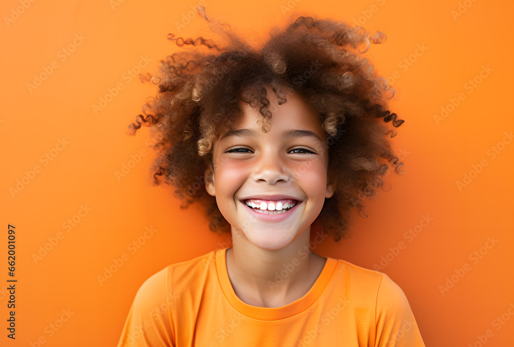 Portrait of a happy laughing boy on an orangel background