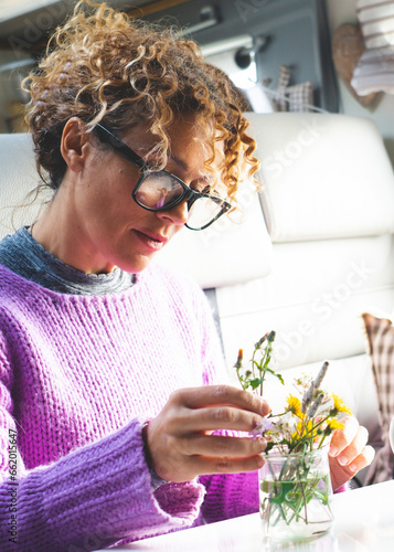 One adult woman caring plants and flowers inside a camper van modern tiny house motorhome rv alone. People living vanlife fulltime. People and nature. Happy young mature female indoor leisure photo