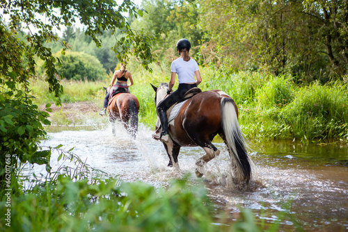 Horse ride, young girls riders, crossing a river on horseback.