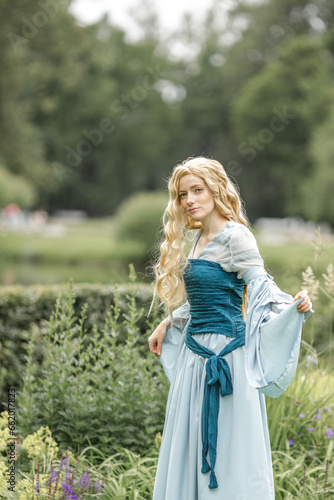A young beautiful girl in a summer park. A beautiful medieval elf princess in a blue dress in the forest
