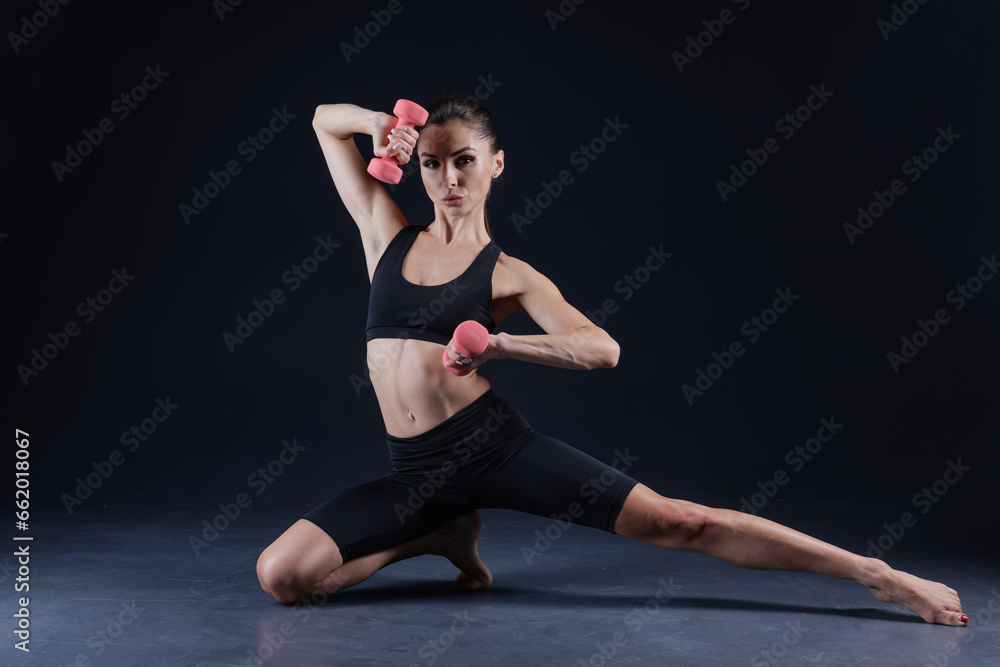 Obraz premium athletic girl in white clothes with dumbbells, on a dark background