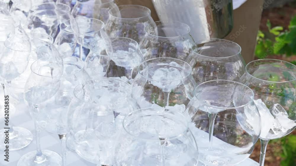 Male hand putting ice in cocktail glasses at outdoor party. Male hand putting ice in cocktail glasses at outdoor party.