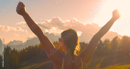CLOSE UP, LENS FLARE: Victorious moment of a lady reaching beautiful mountaintop photo