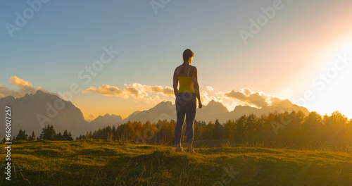 CLOSE UP, LENS FLARE: Sporty woman paused at the top to admire beautiful sunset