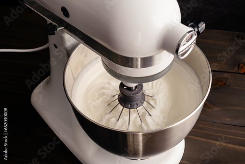 Stand Mixer with a Whisk Attachment in Beaten Egg Whites: Electric mixer in the down position with stiff egg whites in the bowl