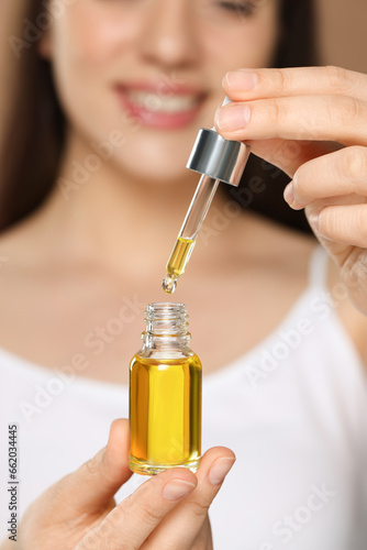 Woman with essential oil on brown background, selective focus