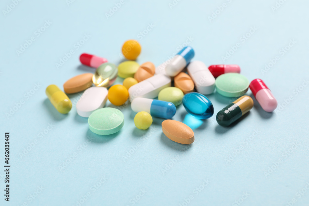 Many different pills on light blue background, closeup Many different pills on light blue background, closeup