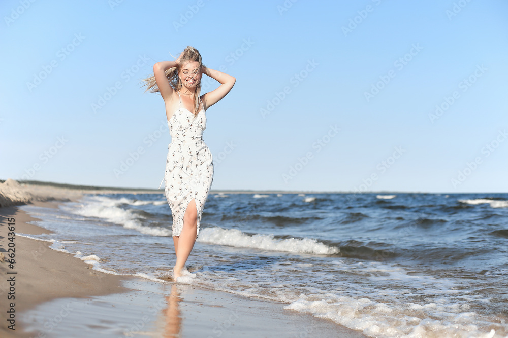 Happy blonde beautiful woman having fun on ocean beach while dancing in waves Happy blonde beautiful woman having fun on ocean beach while dancing in waves